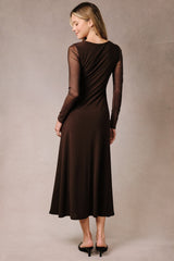 woman wearing a brown long sleeve dress with sheer sleeves and a flowy skirt, seen from the back