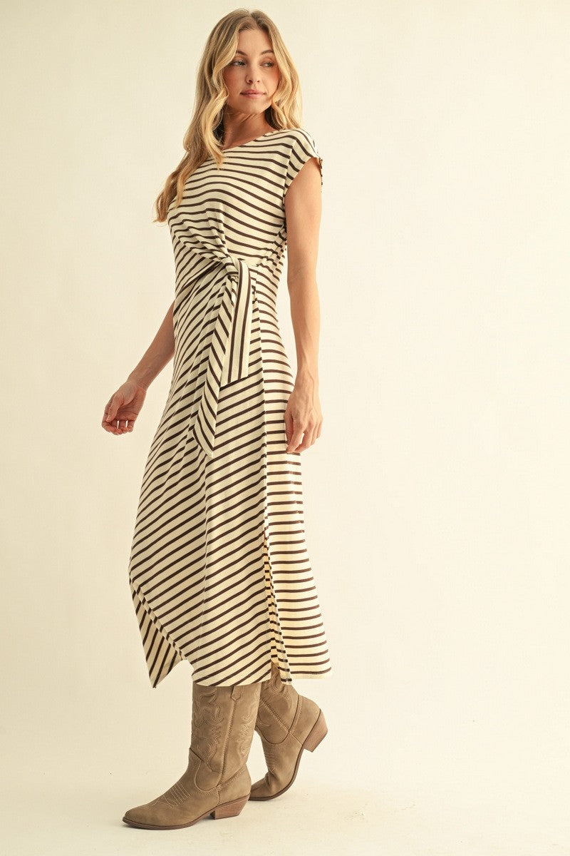 woman wearing a striped midi dress with a tie waist and cap sleeves, paired with beige knee-high boots