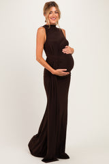 woman wearing a dark brown sleeveless maternity gown, posing and holding her baby bump