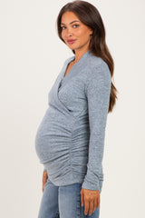 woman wearing a gray long sleeve maternity top with a ruched design, showcasing her baby bump