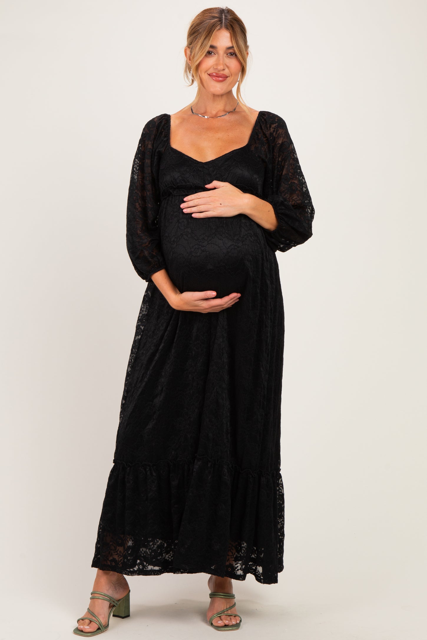 woman wearing a black lace long sleeve maternity dress and holding her baby bump