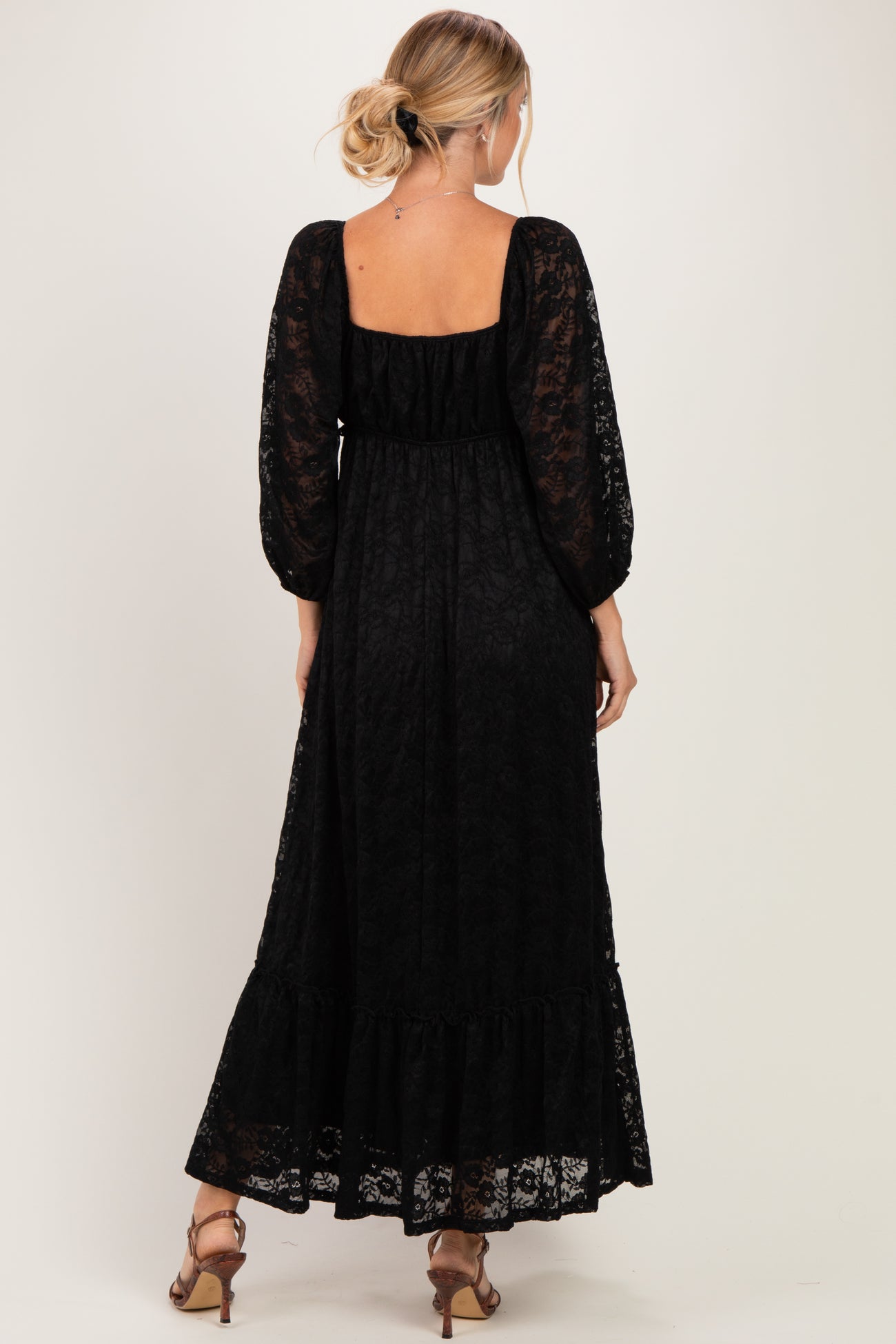 woman wearing a black lace maxi dress with long sleeves and a ruffled hem, viewed from the back