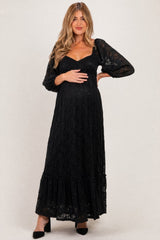 woman wearing a black lace maternity maxi dress with puffed sleeves and holding her baby bump