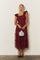 woman wearing a burgundy tiered maxi dress with ruffled straps and holding a silver handbag