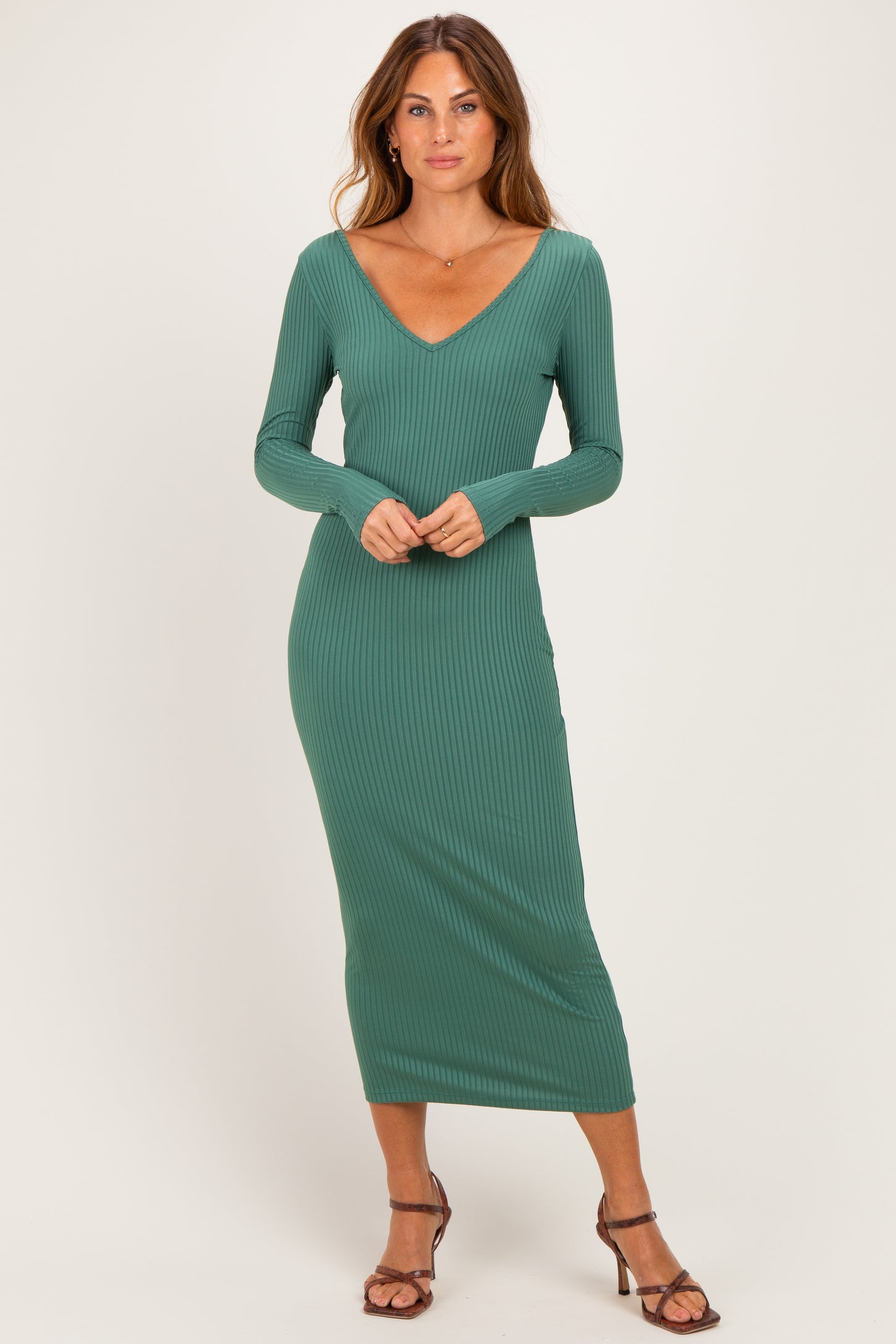 woman wearing a long sleeve green ribbed midi dress with a v-neckline and styled with strappy heels