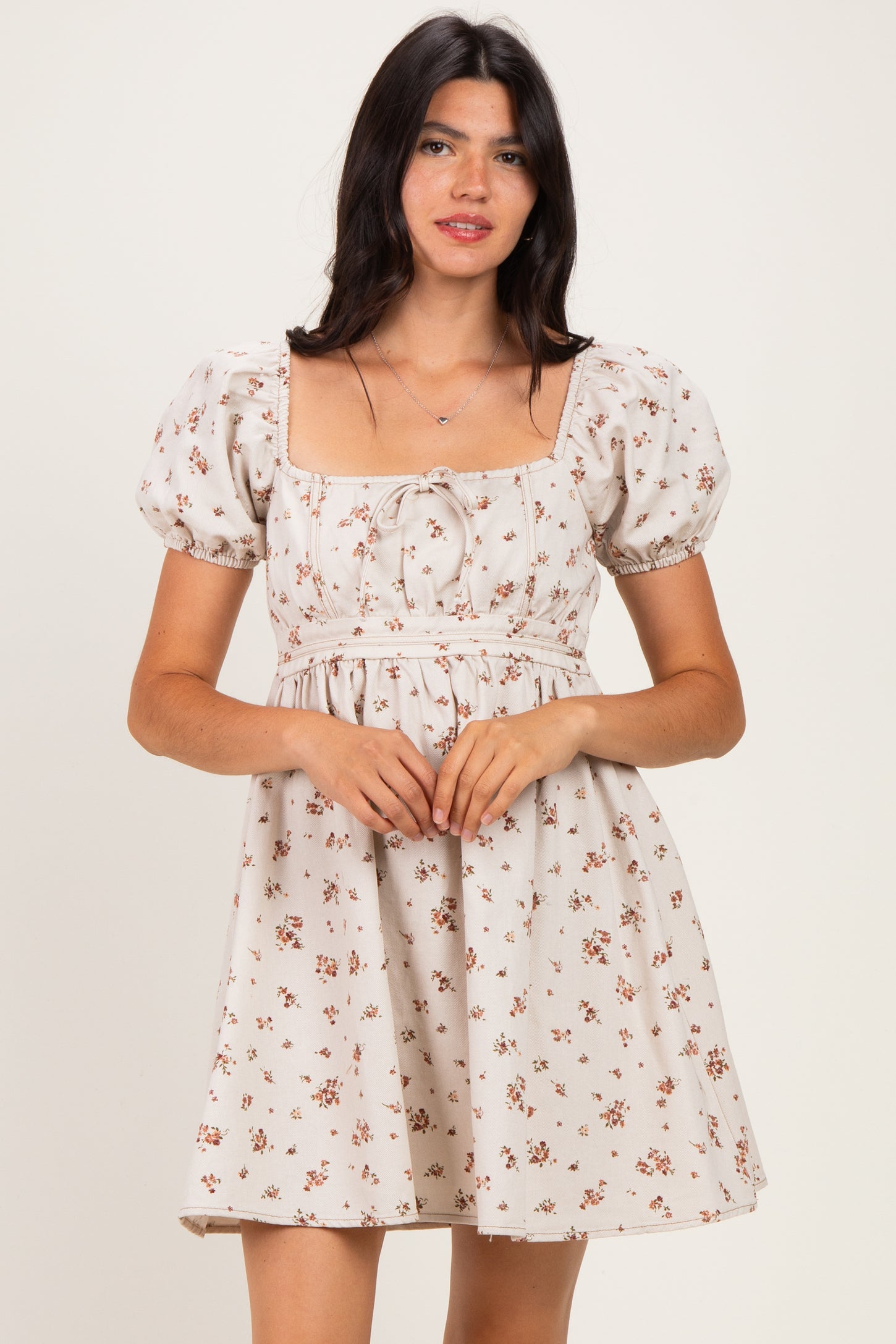 woman wearing a beige floral puff sleeve dress with a square neckline and a cinched waist