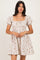 woman wearing a beige floral puff sleeve dress with a square neckline and a cinched waist