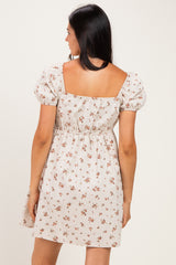 woman wearing a light beige floral short dress with puff sleeves and a fitted waist, shown from the back