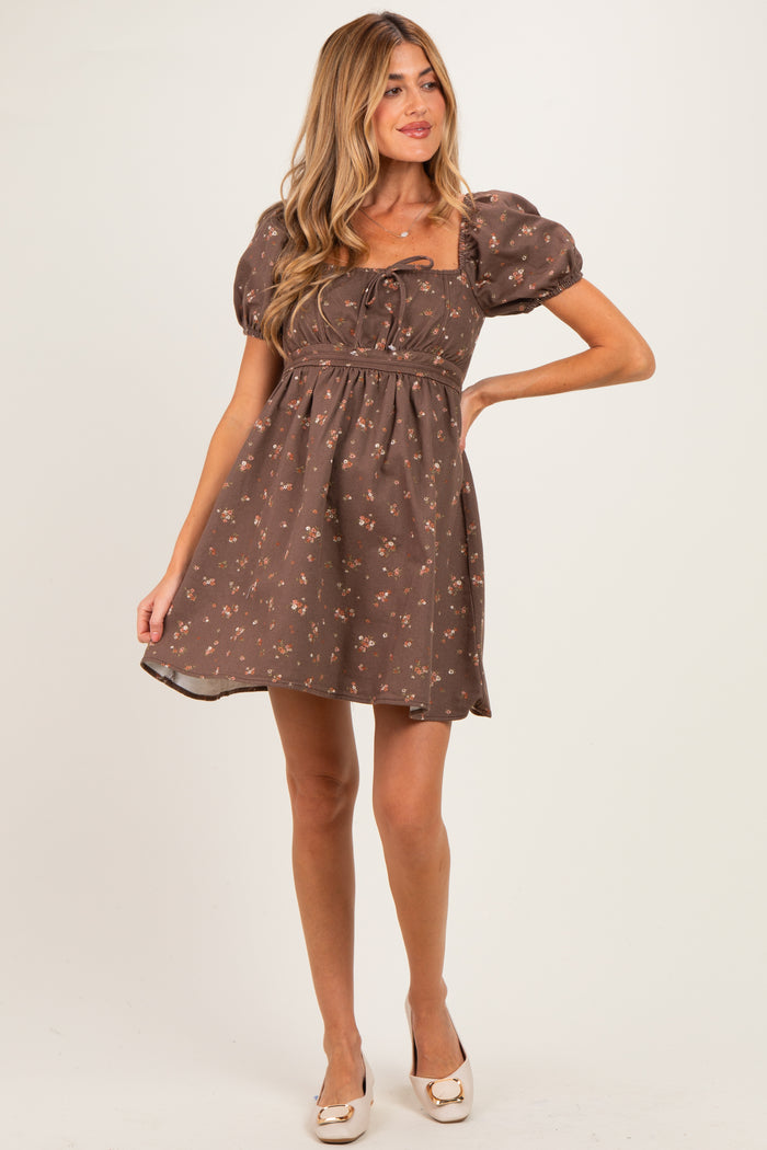 woman wearing a brown floral print maternity dress with puff sleeves and a tied neckline, showing off her baby bump