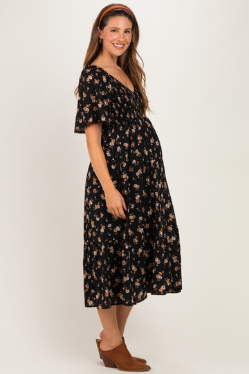 woman wearing a black floral maternity dress with short sleeves and a flowy skirt, accentuating her baby bump