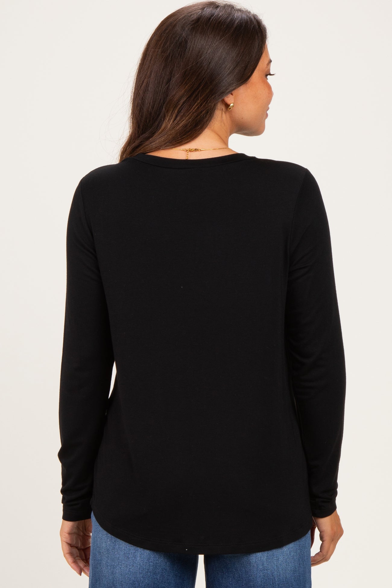woman wearing a black long sleeve maternity top, shown from the back, paired with blue jeans