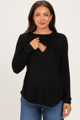 woman wearing a black long sleeve maternity top with a wrap design and a stylish v-neckline, showing her baby bump