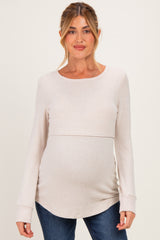 woman wearing a light beige long sleeve maternity top with a curved hem and visible baby bump