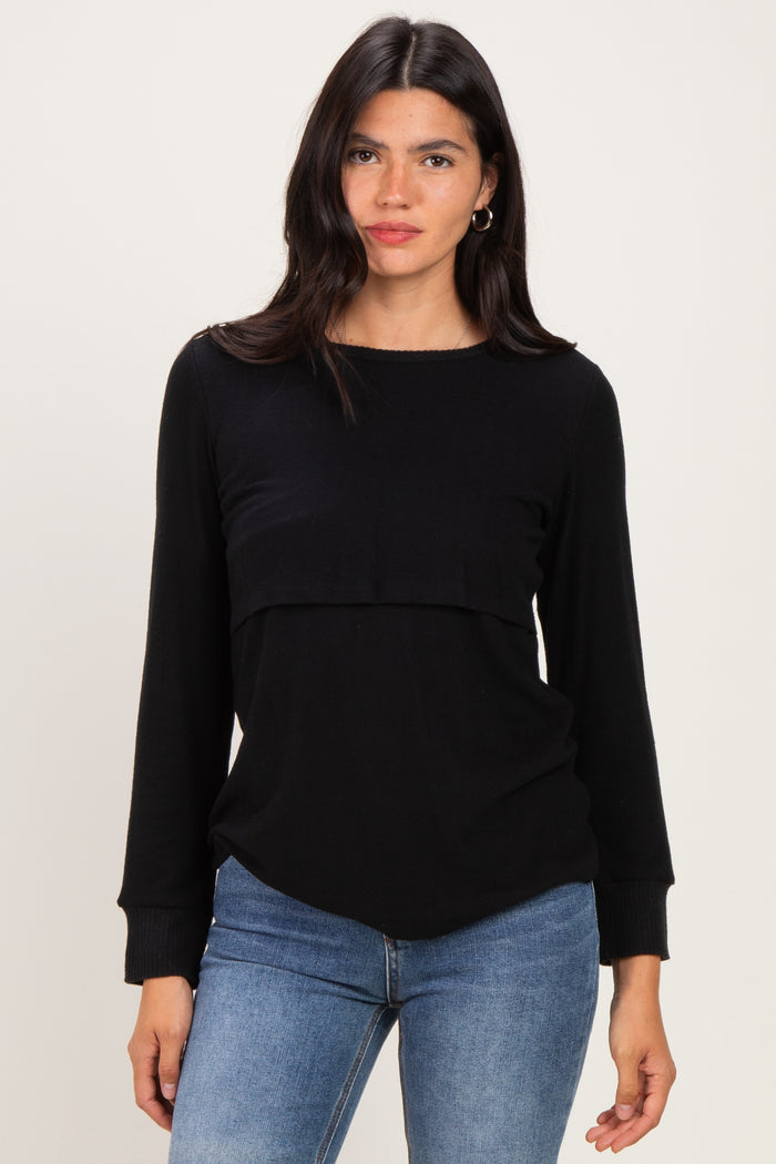 woman wearing a black long sleeve top with a layered design and relaxed fit, paired with blue jeans