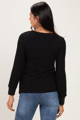 woman wearing a black long sleeve sweater with a fitted style and round neckline, seen from the back
