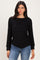 woman wearing a black long sleeve top with a layered design and relaxed fit, paired with blue jeans
