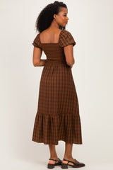 woman wearing a brown plaid puff sleeve midi dress with a smocked bodice and ruffled hem, viewed from the back