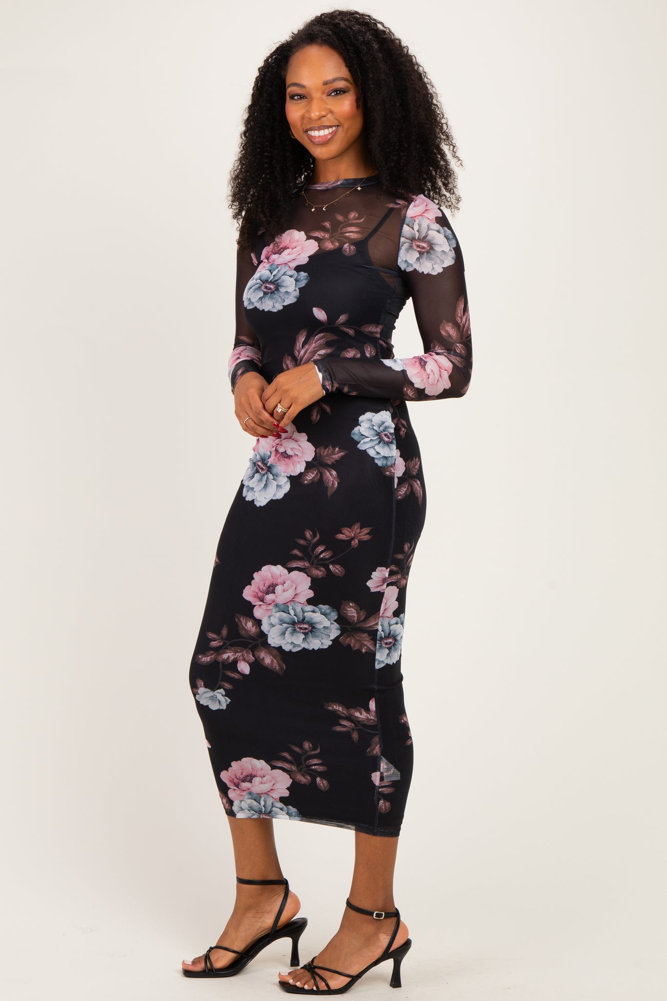 woman wearing a black floral long sleeve midi dress with sheer sleeves and fitted silhouette