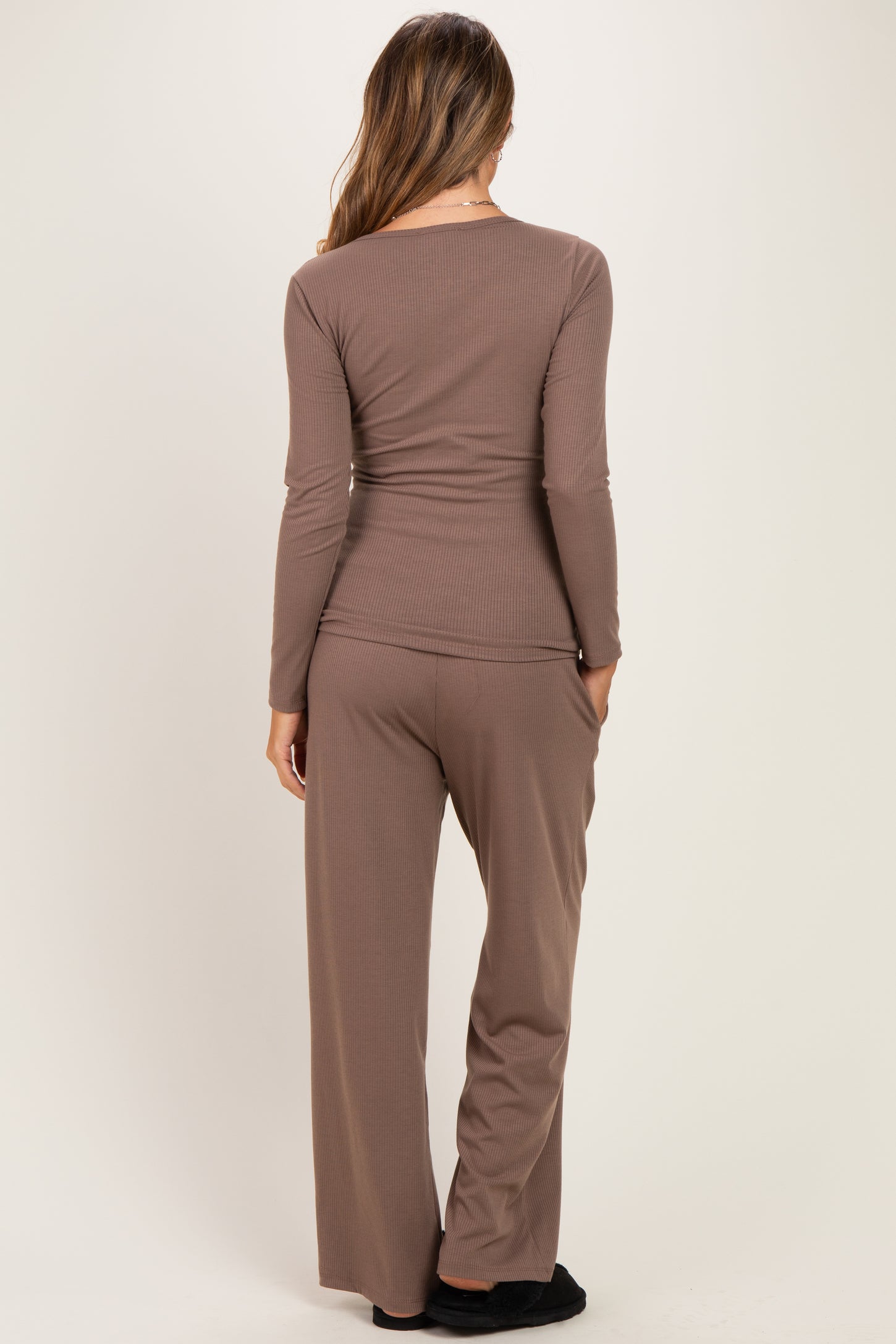 woman wearing a brown long sleeve maternity top and matching pants, viewed from the back