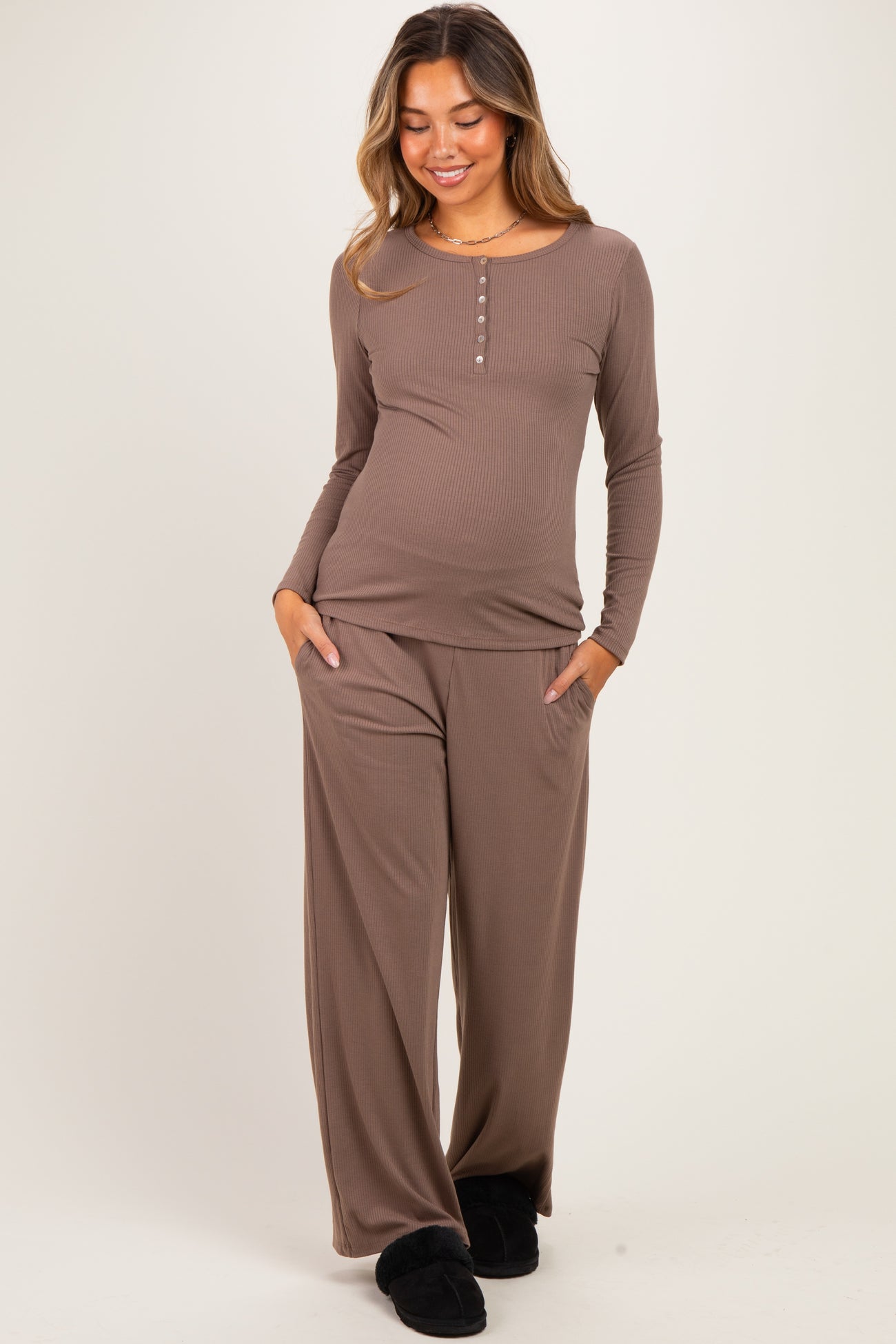 woman wearing a brown long sleeve maternity top with buttons and matching wide-leg pants, showing her baby bump