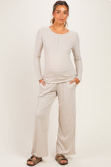 woman wearing a light taupe maternity loungewear set with a long sleeve henley top and wide-leg pants, baby bump visible