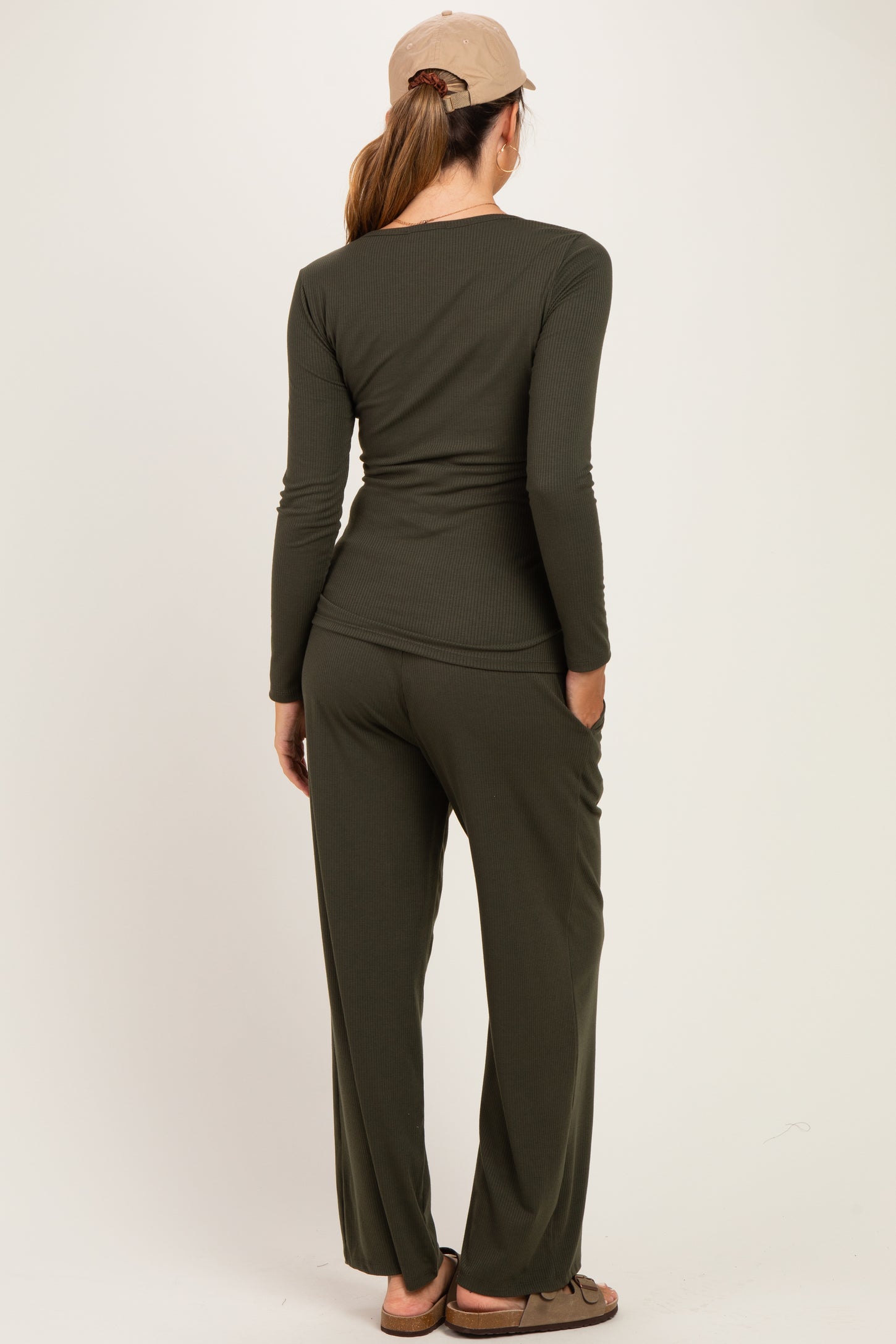 woman wearing a dark green long sleeve maternity top and matching pants, viewed from the back