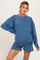 woman wearing a blue oversized sweatshirt and matching shorts, showing her baby bump as maternity wear
