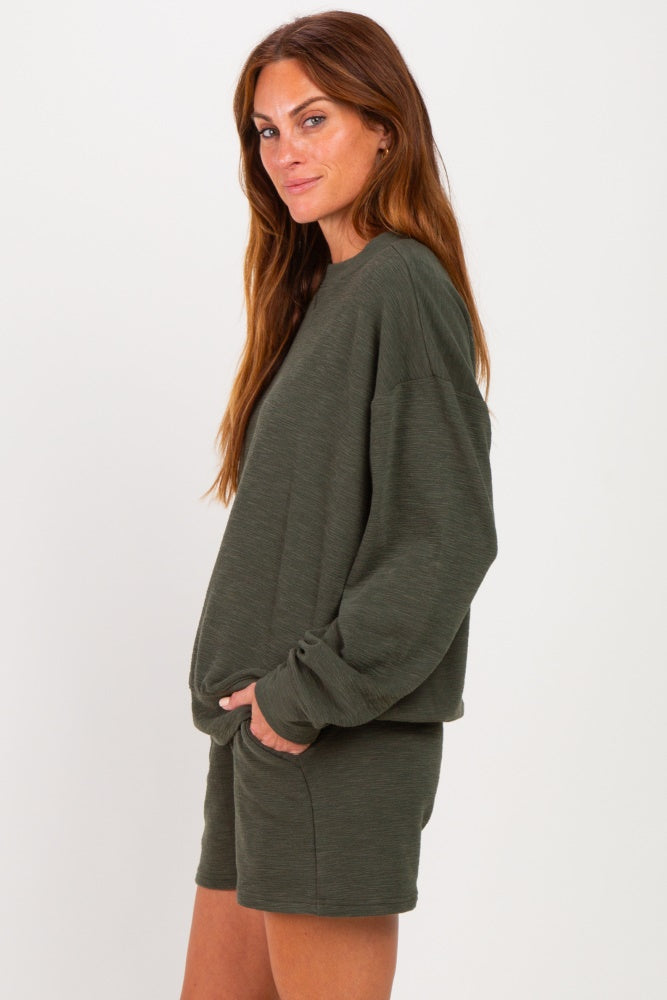 woman wearing an olive green long sleeve pullover sweatshirt and matching shorts, posing sideways