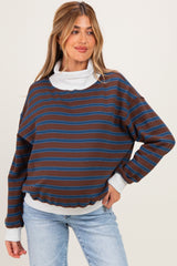 woman wearing a brown striped maternity sweatshirt with a white turtleneck underneath, styled with blue jeans