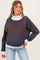 woman wearing a brown striped maternity sweatshirt with a white turtleneck underneath, styled with blue jeans