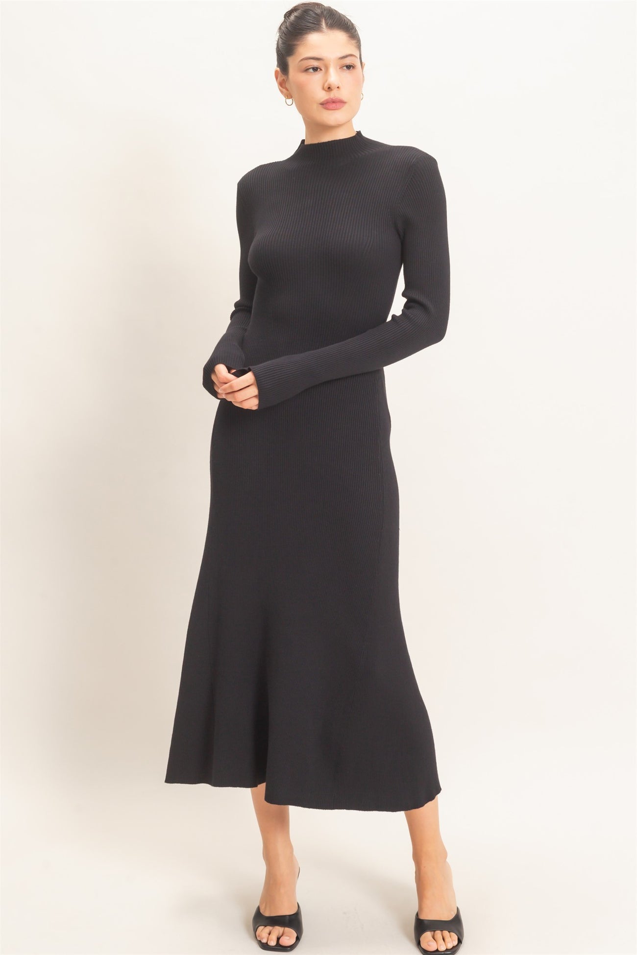 woman wearing a black long sleeve ribbed knit midi dress with a fitted bodice and flared skirt