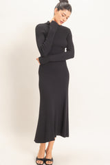 woman wearing a black ribbed knit long sleeve midi dress with a high neckline and a flared hemline
