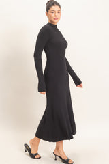 woman wearing a black long-sleeve ribbed midi dress with a flared hem and open-toe heels