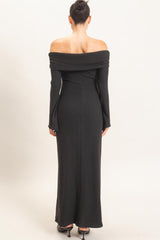 woman wearing a black off-the-shoulder ribbed maxi dress from the back with long sleeves and a fitted silhouette