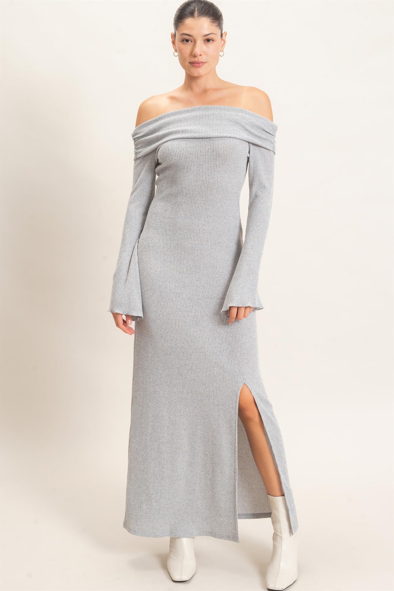 woman wearing a gray off-the-shoulder ribbed maxi dress with long sleeves and a side slit