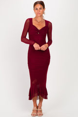 woman wearing a burgundy long sleeve fitted midi dress with ruffle hem and a front twist detail