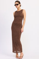 woman wearing a brown lace maxi dress with a fitted silhouette and sunglasses, posing sideways