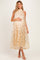 woman wearing a flowy beige maternity dress with floral embroidery, gently cradling her baby bump