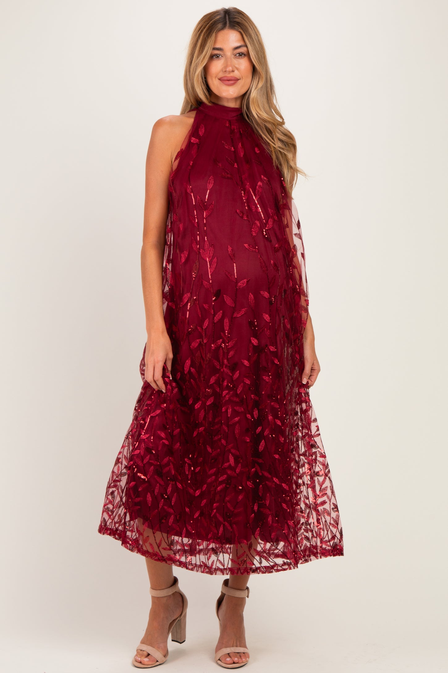 woman wearing a burgundy maternity dress with floral embroidery and a flowy silhouette, showcasing her baby bump