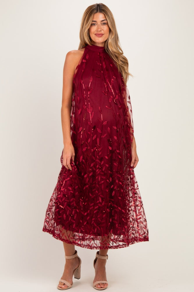 woman wearing a burgundy maternity dress with floral embroidery and a flowy silhouette, showcasing her baby bump