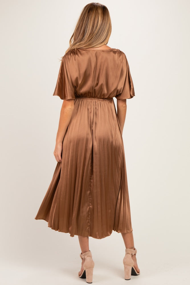 woman wearing a bronze satin pleated maternity dress with short sleeves and an elastic waist, showing the back view
