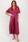 woman wearing a burgundy pleated maxi dress with flutter sleeves and a tie at the waist