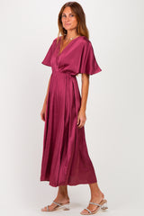 woman wearing a burgundy silk v-neck maxi dress with flutter sleeves and a cinched waist