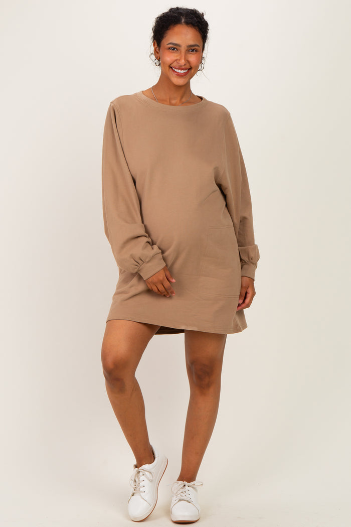 woman wearing a beige long sleeve maternity dress with a relaxed fit and pockets, showcasing her baby bump