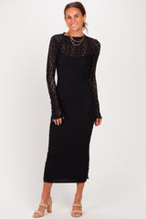 woman wearing a long sleeve black fitted dress with lace details and a midi length, standing and smiling