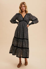 woman wearing a black floral print maxi dress with puff sleeves and tiered skirt