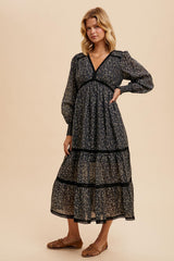 woman wearing a black floral midi dress with tiered layers and puff sleeves, styled with flat sandals