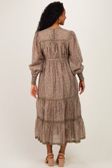 woman wearing a brown floral maternity dress with long sleeves and tiered ruffle hem, showcasing a baby bump