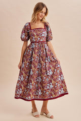 woman wearing a burgundy floral maxi dress with puff sleeves and a square neckline