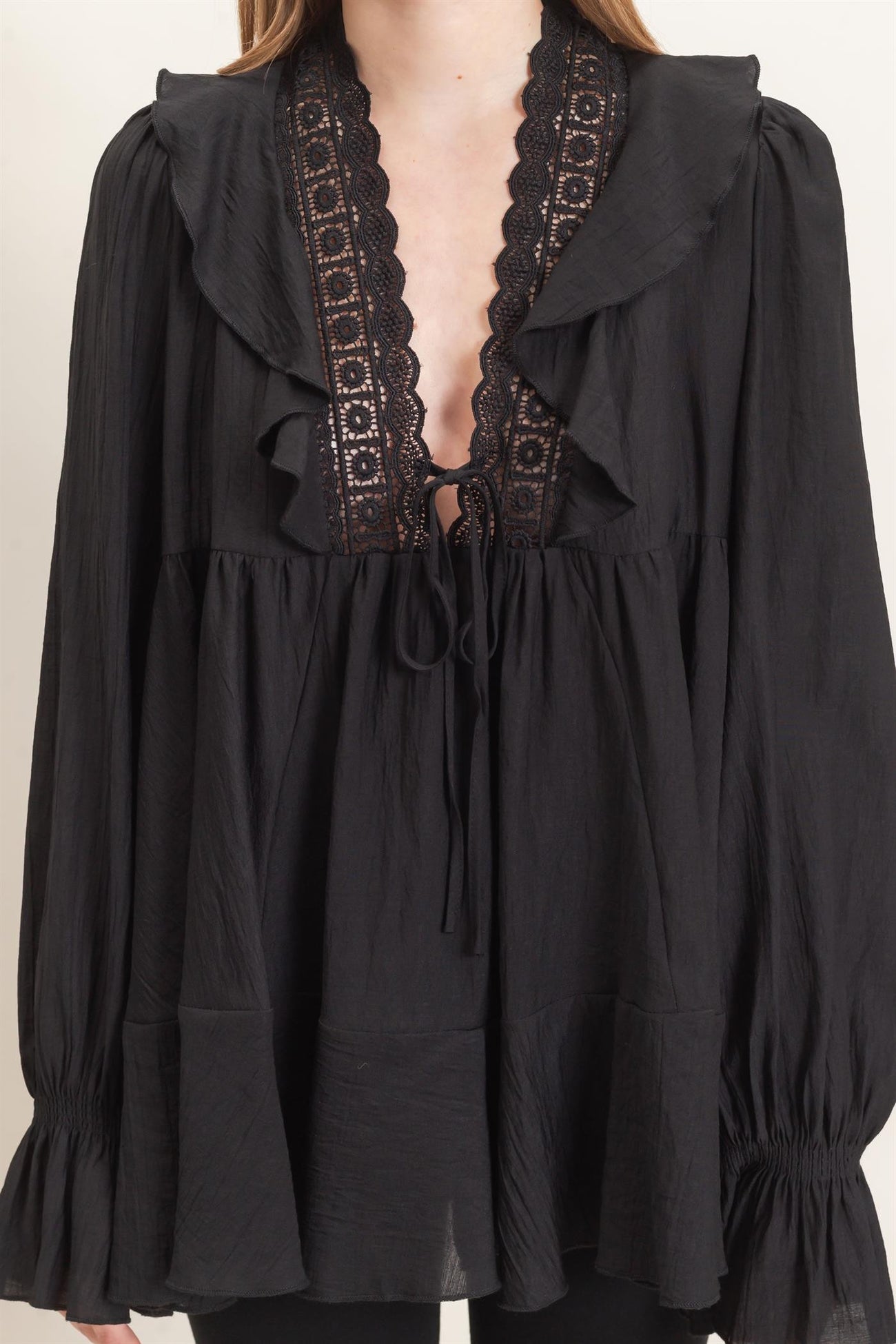 woman wearing a black ruffled blouse with lace details and long sleeves